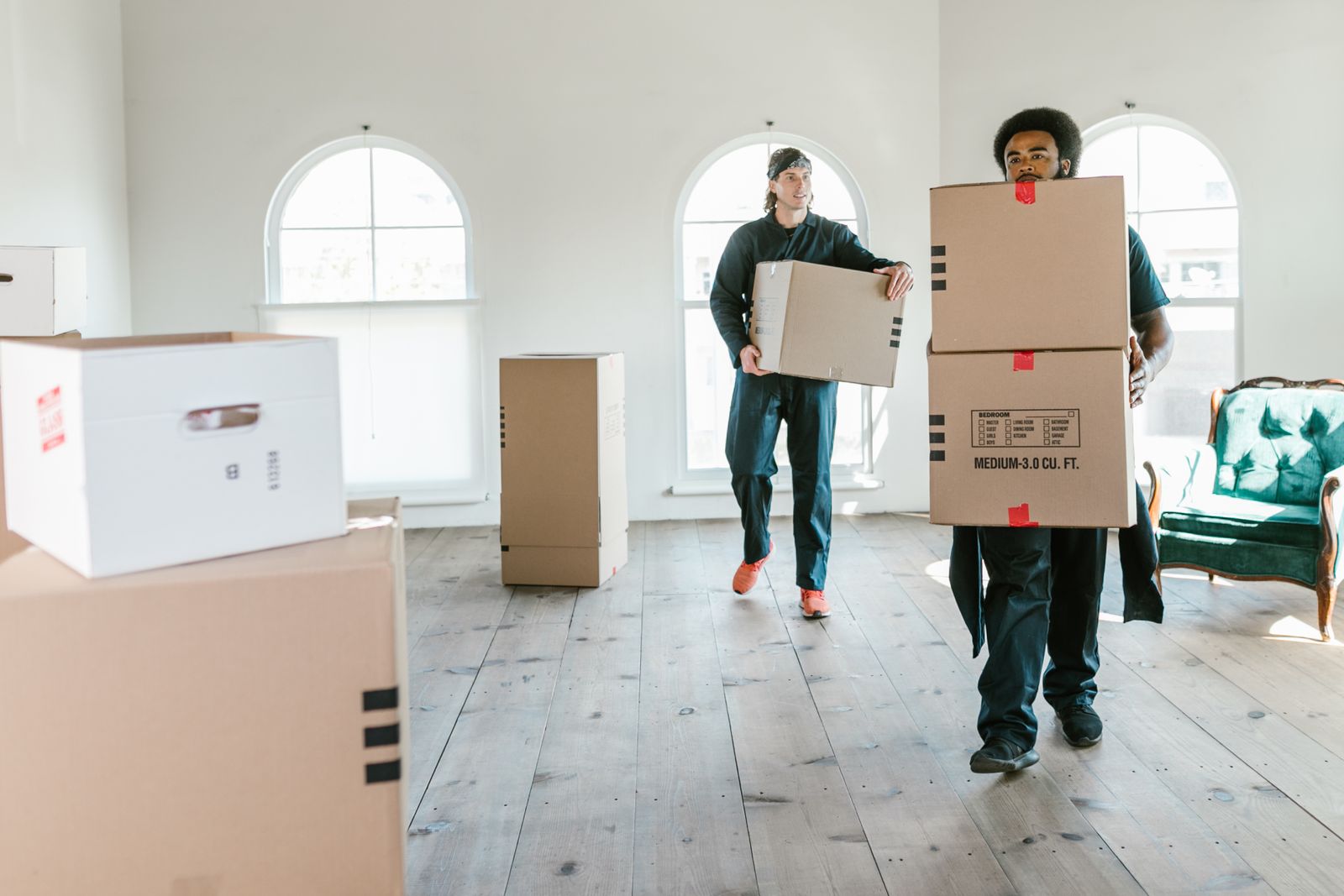 Eingespieltes Umzugsteam von Hauptstadt Umzüge trägt Kartons durch eine helle Wohnung